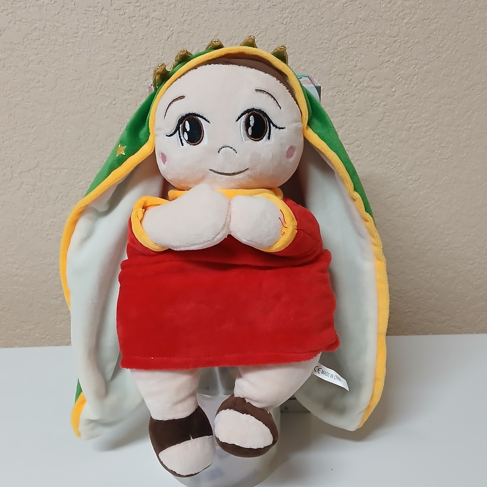 Virgen Plush in Red Dress with Green Hood prays In Spanish.
